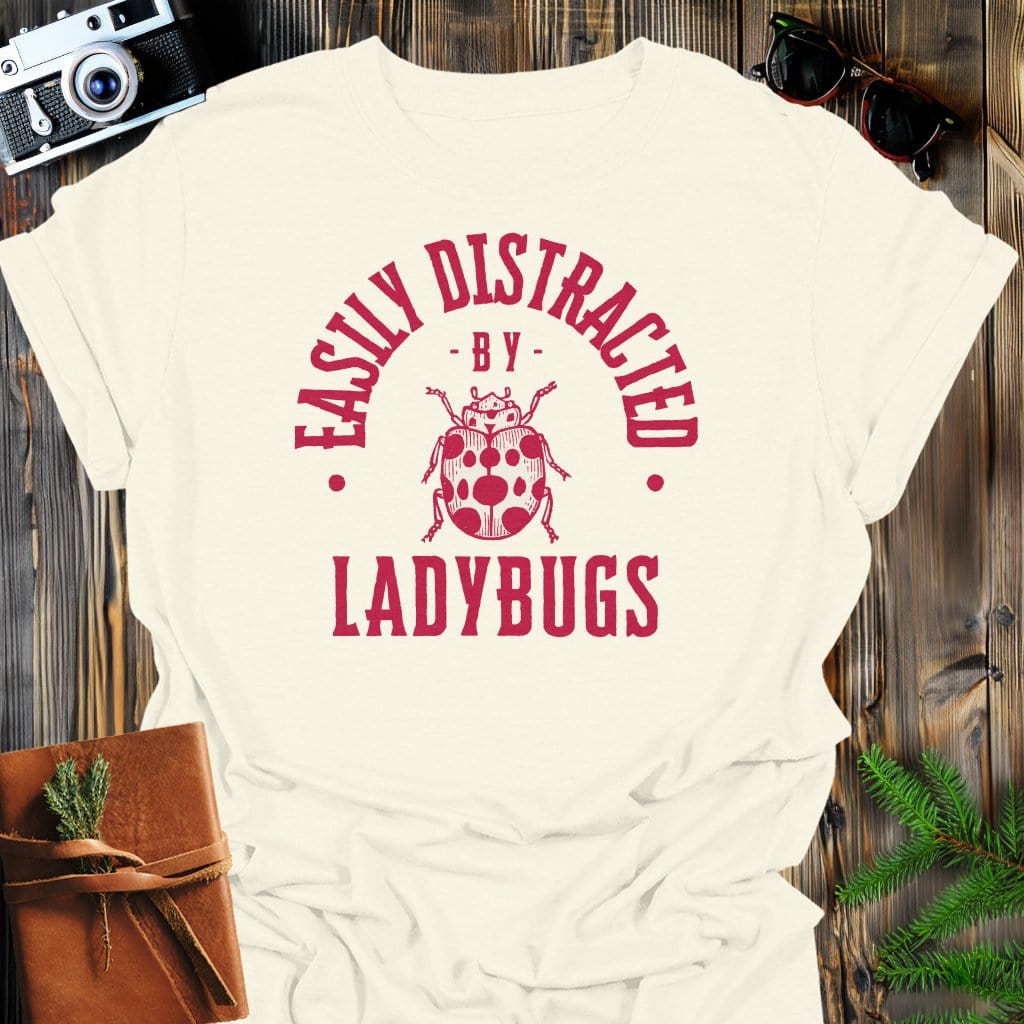 Distracted By Ladybugs T-Shirt In S / Natural Lightweight adventure tee for outdoor lovers Perfect for hiking camping or road trips Made from soft breathable cotton for all-day comfort Ideal for nature lovers and adventurers FAYO Threads outdoor apparel remember Fun Awaits You Outside