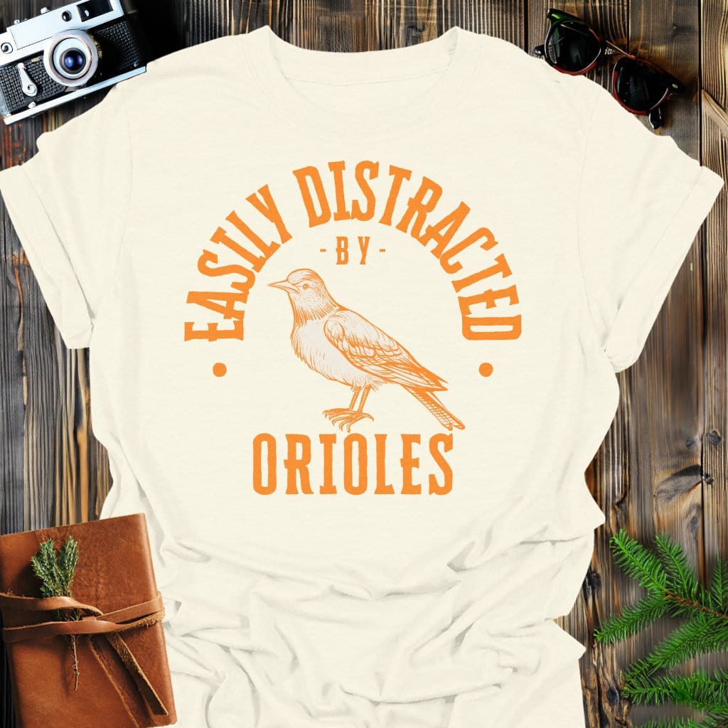 Distracted by Orioles T-Shirt In S / Natural Lightweight adventure tee for outdoor lovers Perfect for hiking camping or road trips Made from soft breathable cotton for all-day comfort Ideal for nature lovers and adventurers FAYO Threads outdoor apparel remember Fun Awaits You Outside