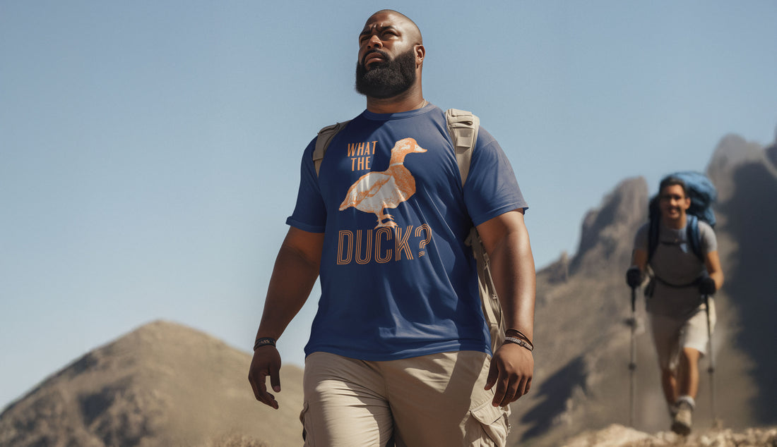 Hiker wearing a blue 'What the Duck?' graphic t-shirt from FAYO Threads, walking confidently on a sunny mountain trail with another hiker in the background