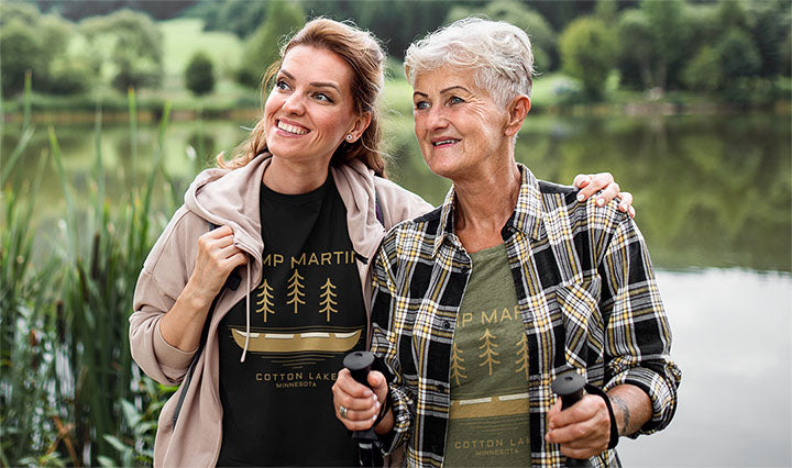 Two women wearing personalized nature-inspired shirts by a lake, enjoying an outdoor adventure by a lake.