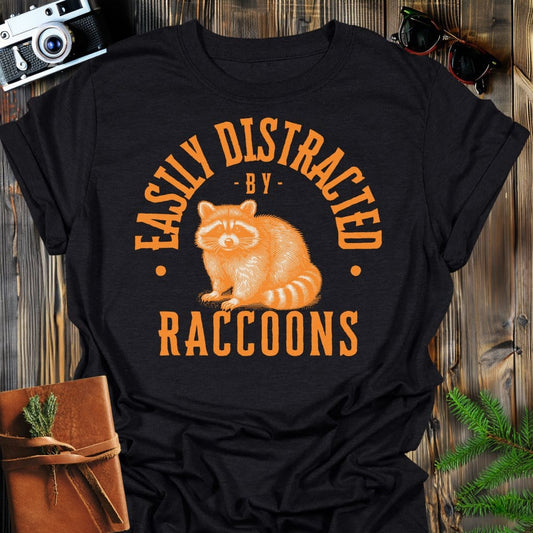 Distracted by Raccoons T-Shirt In S / Black Lightweight adventure tee for outdoor lovers Perfect for hiking camping or road trips Made from soft breathable cotton for all-day comfort Ideal for nature lovers and adventurers FAYO Threads outdoor apparel remember Fun Awaits You Outside