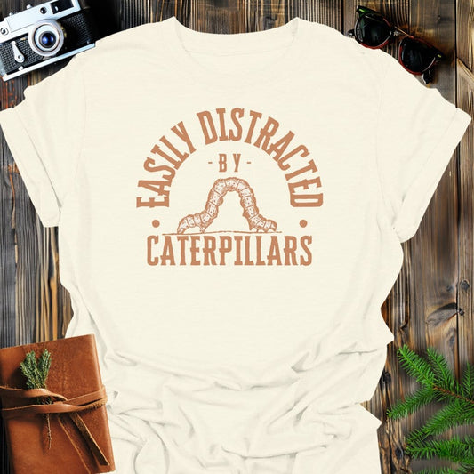 Distracted By Catepillars T-Shirt In S / Natural Lightweight adventure tee for outdoor lovers Perfect for hiking camping or road trips Made from soft breathable cotton for all-day comfort Ideal for nature lovers and adventurers FAYO Threads outdoor apparel remember Fun Awaits You Outside