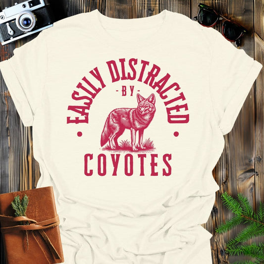 Distracted by Coyotes T-Shirt In S / Natural Lightweight adventure tee for outdoor lovers Perfect for hiking camping or road trips Made from soft breathable cotton for all-day comfort Ideal for nature lovers and adventurers FAYO Threads outdoor apparel remember Fun Awaits You Outside