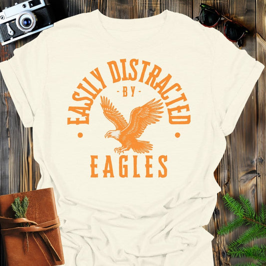 Distracted by Eagles T-Shirt In S / Natural Lightweight adventure tee for outdoor lovers Perfect for hiking camping or road trips Made from soft breathable cotton for all-day comfort Ideal for nature lovers and adventurers FAYO Threads outdoor apparel remember Fun Awaits You Outside