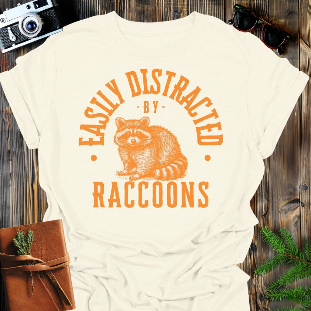 Distracted by Raccoons T-Shirt In S / Natural Lightweight adventure tee for outdoor lovers Perfect for hiking camping or road trips Made from soft breathable cotton for all-day comfort Ideal for nature lovers and adventurers FAYO Threads outdoor apparel remember Fun Awaits You Outside