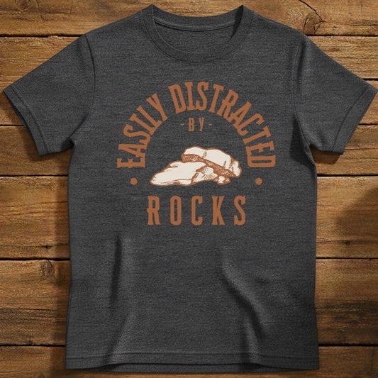 Distracted by Rocks T-Shirt In Dark Heather / S Lightweight adventure tee for outdoor lovers Perfect for hiking camping or road trips Made from soft breathable cotton for all-day comfort Ideal for nature lovers and adventurers FAYO Threads outdoor apparel remember Fun Awaits You Outside