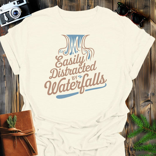 Distracted by Waterfalls T-Shirt In Natural / S Lightweight adventure tee for outdoor lovers Perfect for hiking camping or road trips Made from soft breathable cotton for all-day comfort Ideal for nature lovers and adventurers FAYO Threads outdoor apparel remember Fun Awaits You Outside