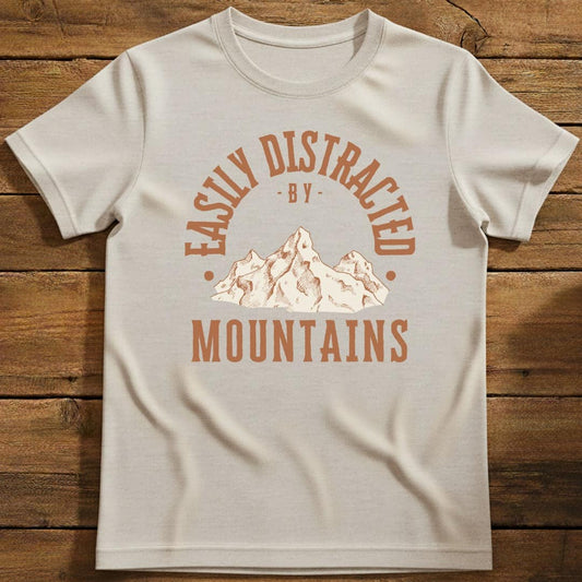 Distracted by Mountains T-Shirt In S / Natural Lightweight adventure tee for outdoor lovers Perfect for hiking camping or road trips Made from soft breathable cotton for all-day comfort Ideal for nature lovers and adventurers FAYO Threads outdoor apparel remember Fun Awaits You Outside